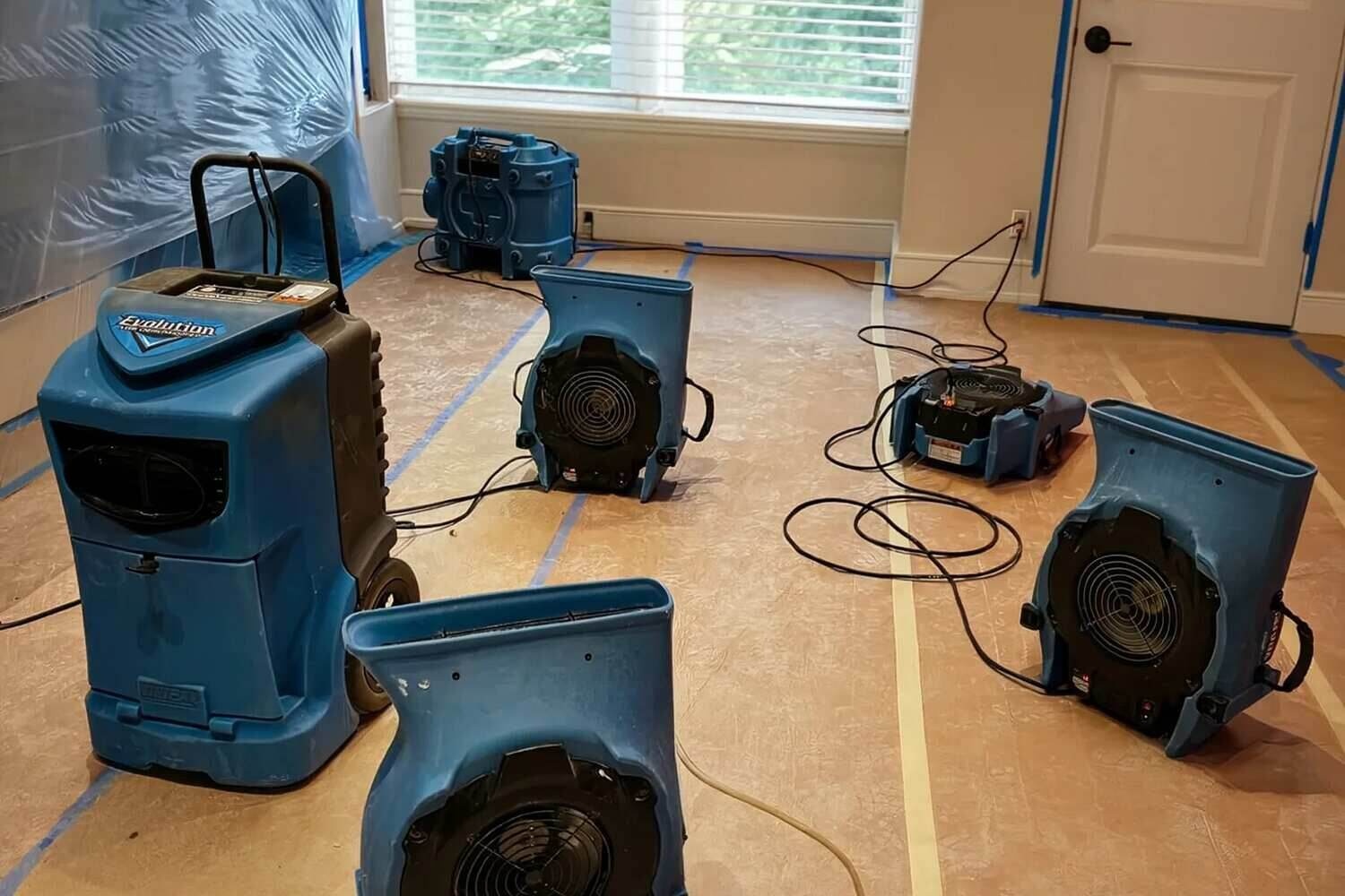 Air movers and a dehumidifier drying a water-damaged Brooklyn room